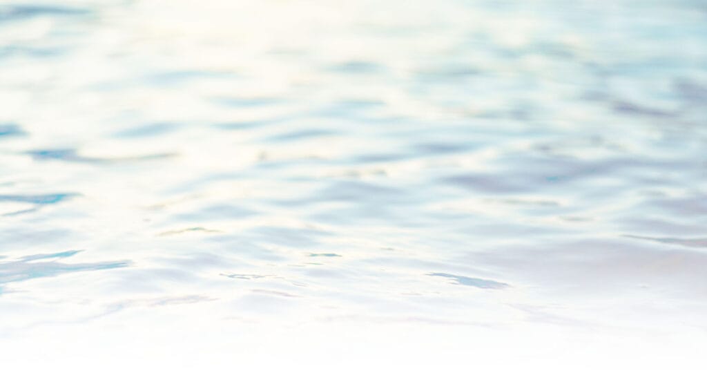 Close-up of light blue water with gentle ripples and soft reflections, creating a calm and serene atmosphere.