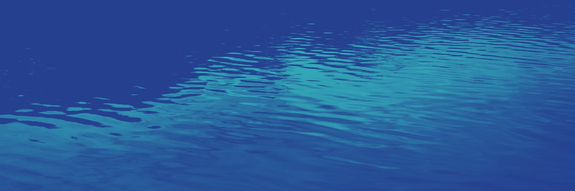 A close-up view of gently rippling blue water, showing reflections and subtle light variations on the surface.